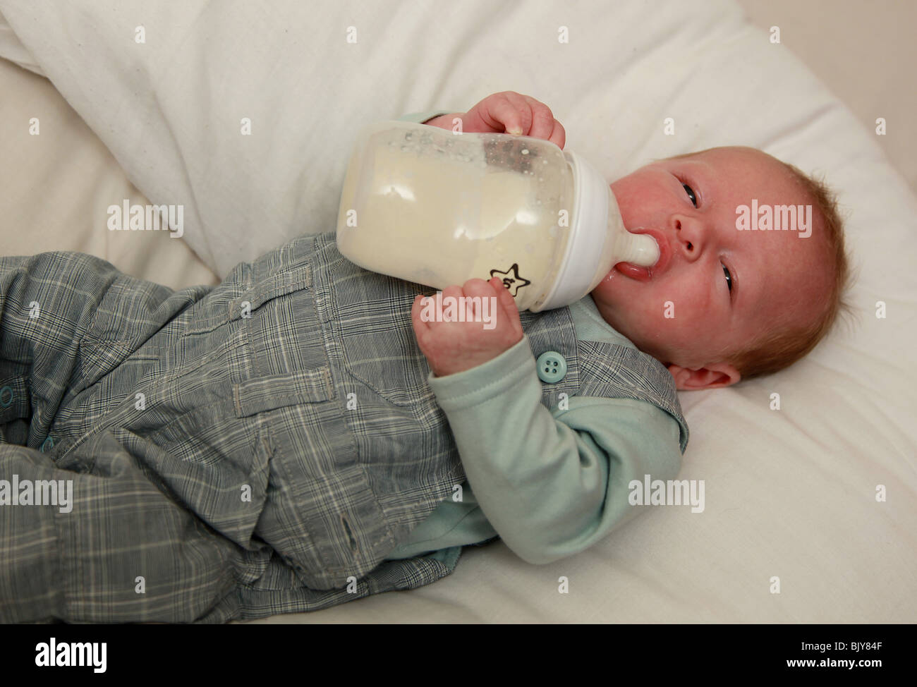 5 settimana di età bambino sdraiato tenendo la bottiglia Foto Stock