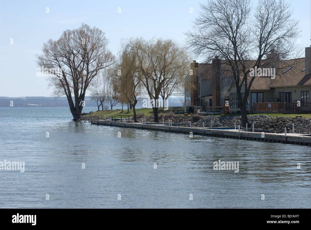 Alloggiamento e alberi acqua di confine accesso al lago Canandaigua NY. Inizio della primavera gemme sugli alberi. Foto Stock
