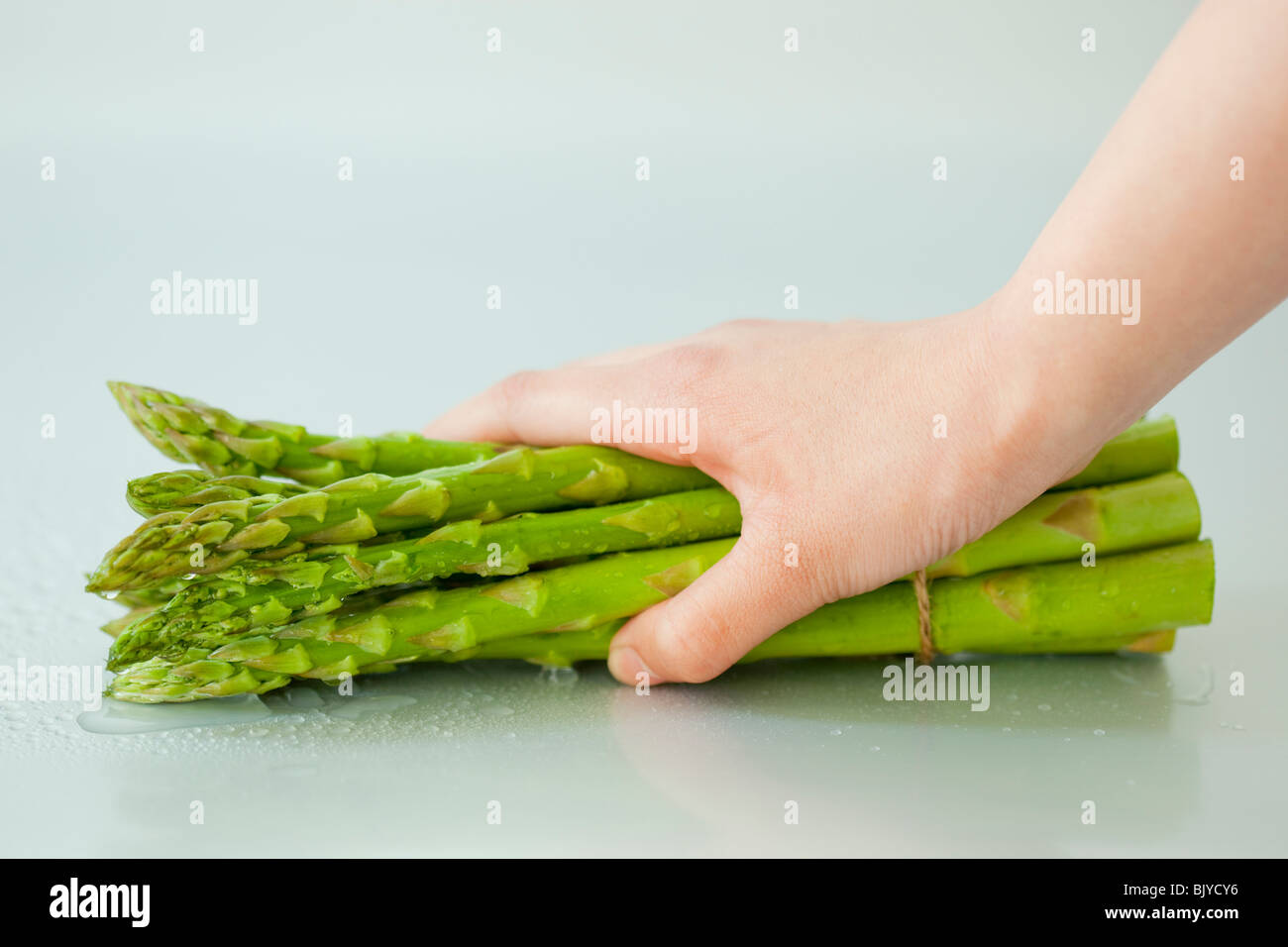 La mano di una donna tenendo un mazzetto di asparagi Foto Stock