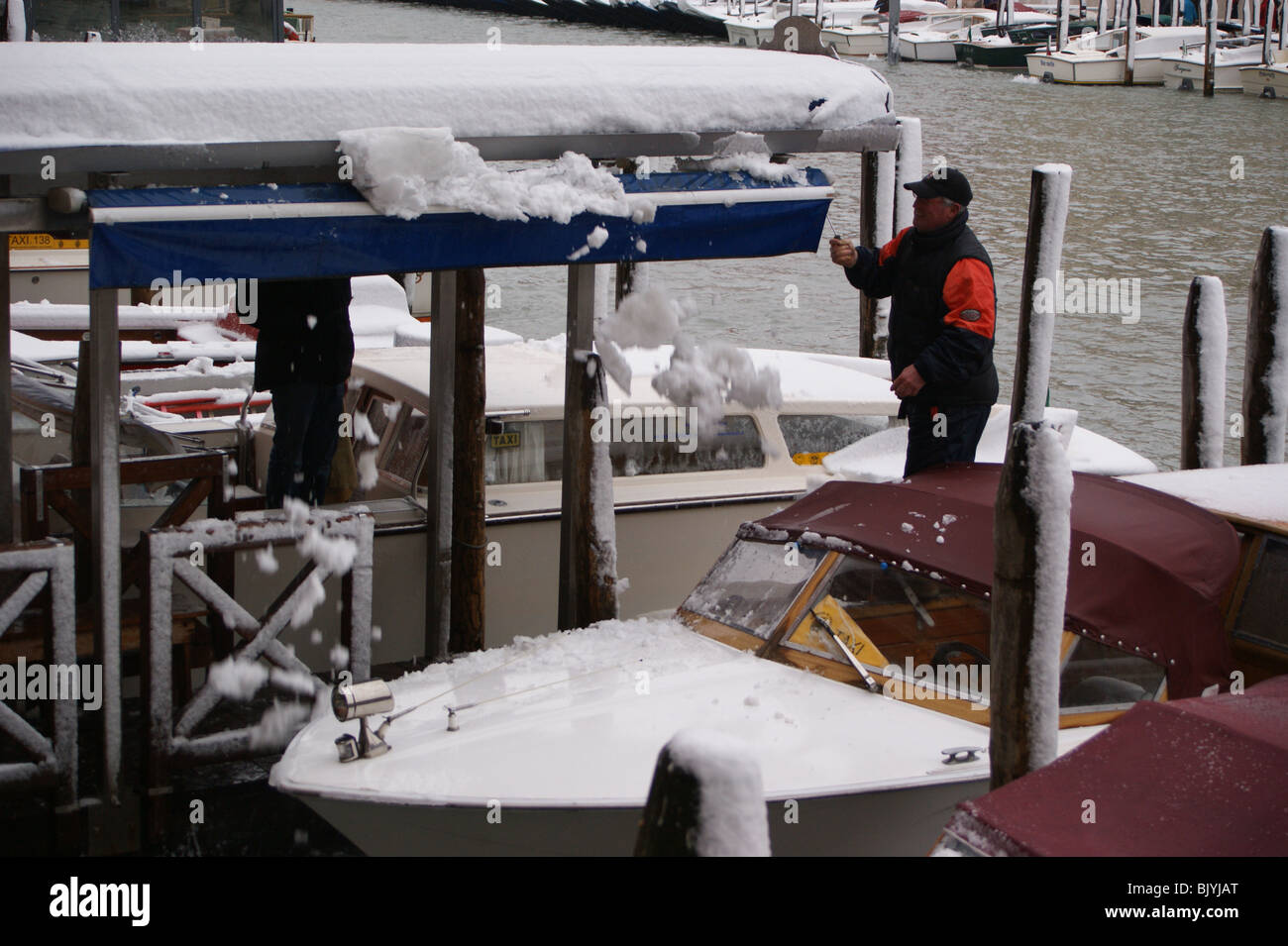 Venezia nella neve - i taxi d'acqua, il Canal Grande. Un taxi skipper cancella la neve da un baldacchino Foto Stock