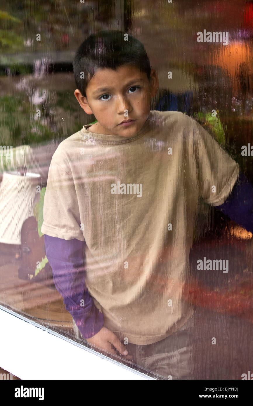 Multicultural multi-culturale di 9 -10 anni vecchio ragazzo ispanico guardando fuori attraverso una finestra in un giorno di pioggia. Bambino faccia triste signor © Myrleen Pearson Foto Stock