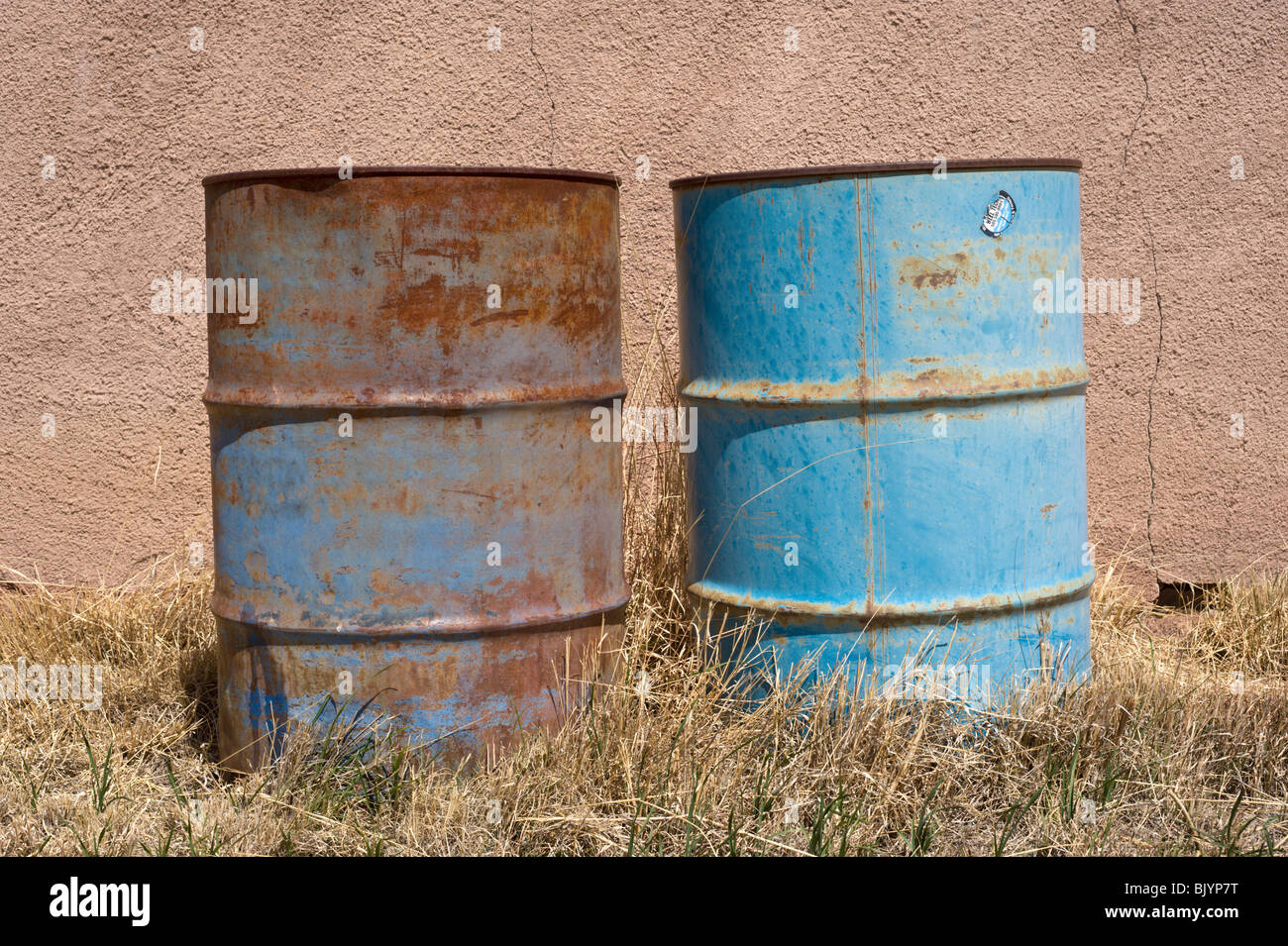 Due blue 55 gallone tamburi ruggine sedersi di fronte a un muro di adobe in Billy the Kid's wild west town di Lincoln, Nuovo Messico. Foto Stock