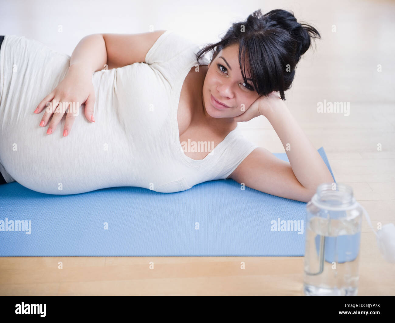 Incinta donna ispanica posa sul materassino yoga Foto Stock