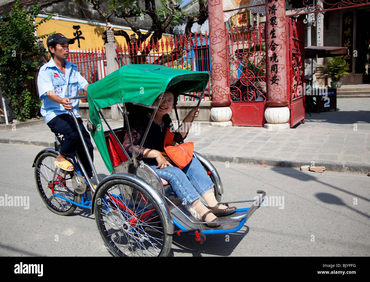 Corsa in Rickshaw al di fuori del Guangdong Hall di Hoi An, Vietnam. Foto Stock