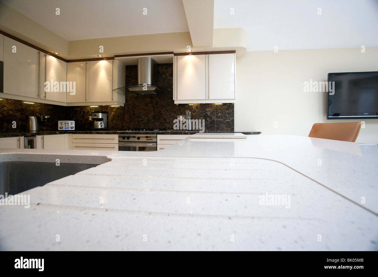 Luminosa e moderna cucina / soggiorno con cucina attrezzata e bancone di marmo alto e un isola di quarzo. Casa di famiglia e area soggiorno. Foto Stock