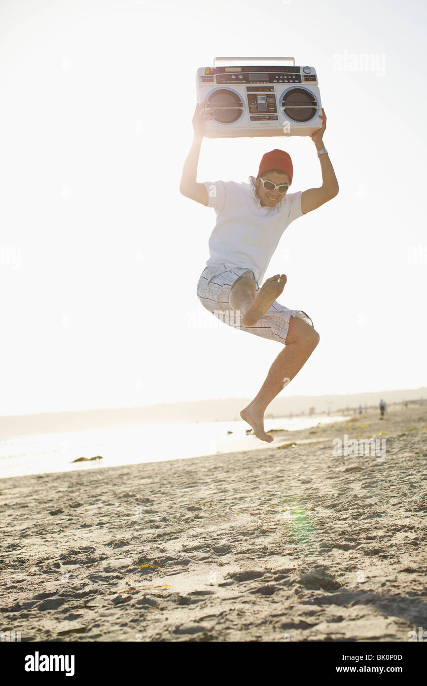 Uomo ispanico holding boom box e jumping Foto Stock