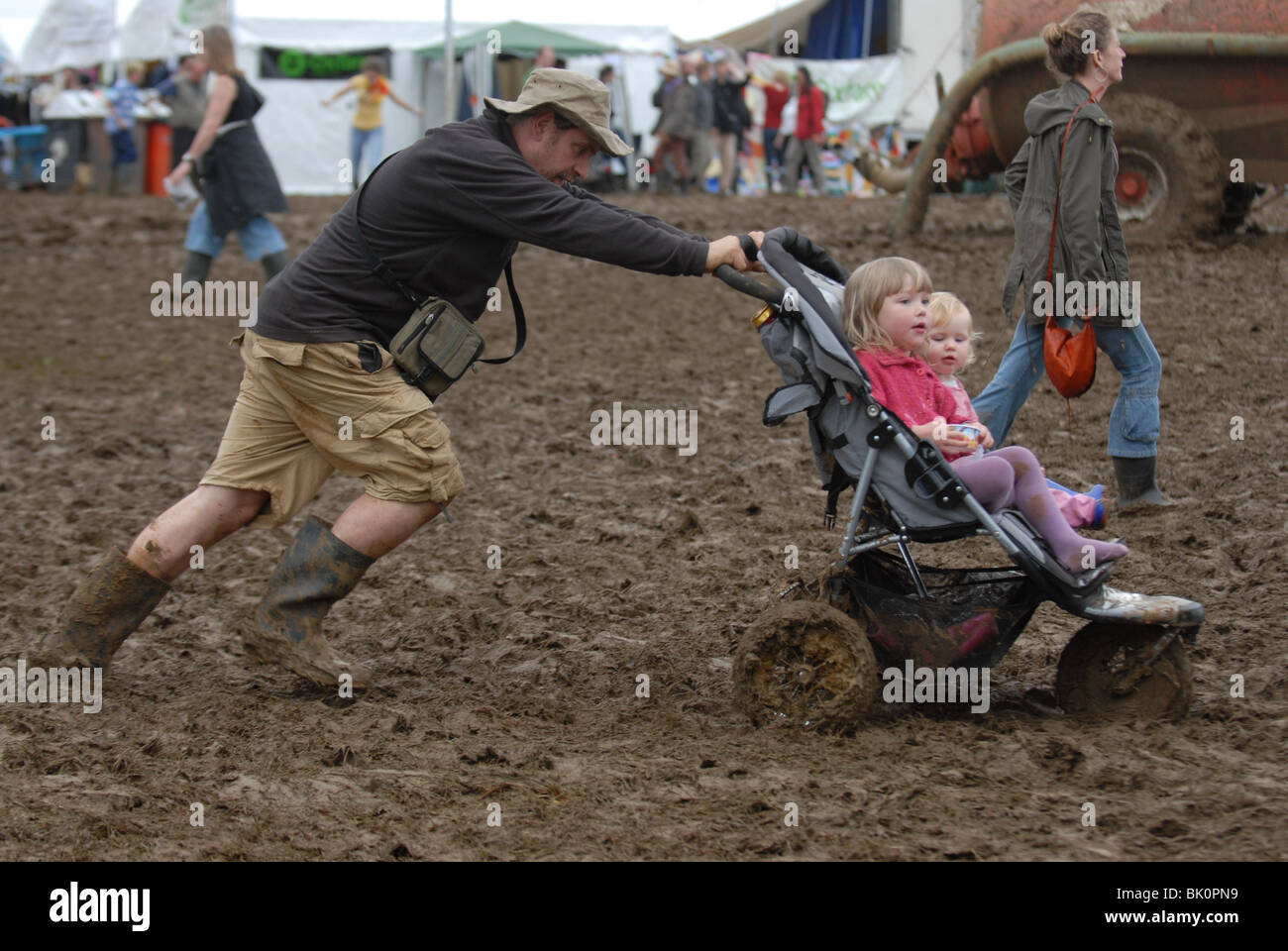 L'uomo lotte con passeggino attraverso il fango spesso al Womad Festival di musica Foto Stock