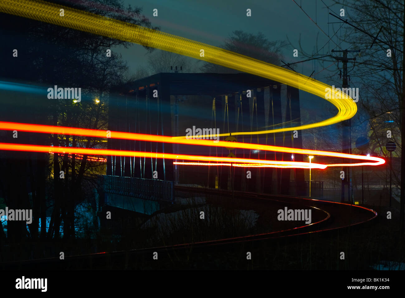 Sentieri di luce da un treno che passa su un ponte ferroviario di notte, tempo di esposizione lungo. Foto Stock
