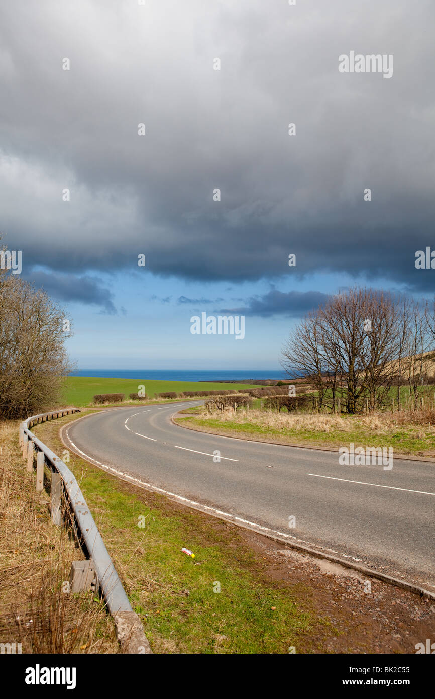 La strada che conduce al Berwickshire costa con cielo tempestoso sopra. Foto Stock