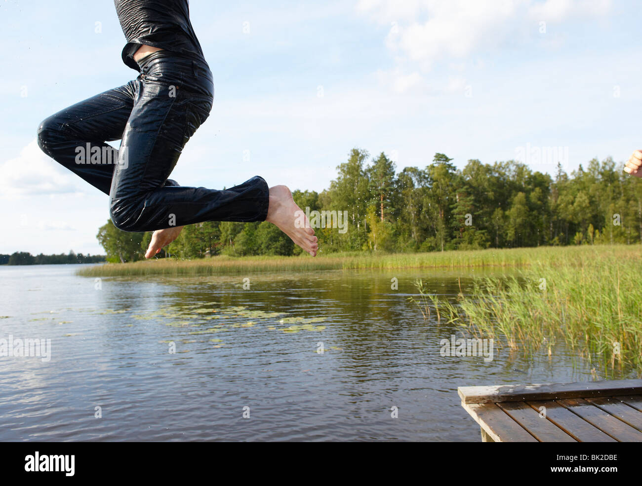 Uomo di saltare nel lago con le sue vesti Foto Stock