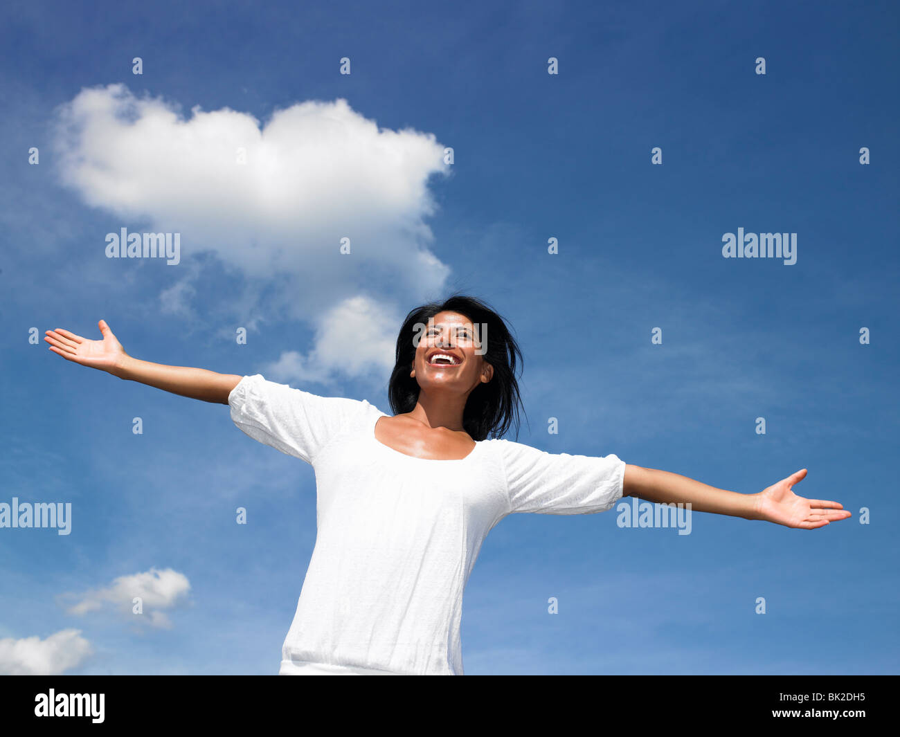 Donna allarga le braccia verso il cielo Foto Stock