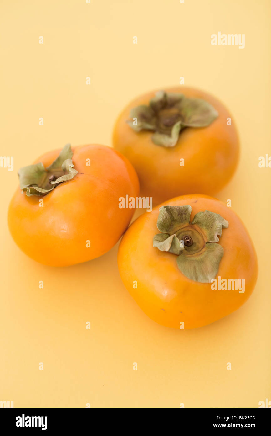 Tre frutti persimmon su uno sfondo colorato. Foto Stock