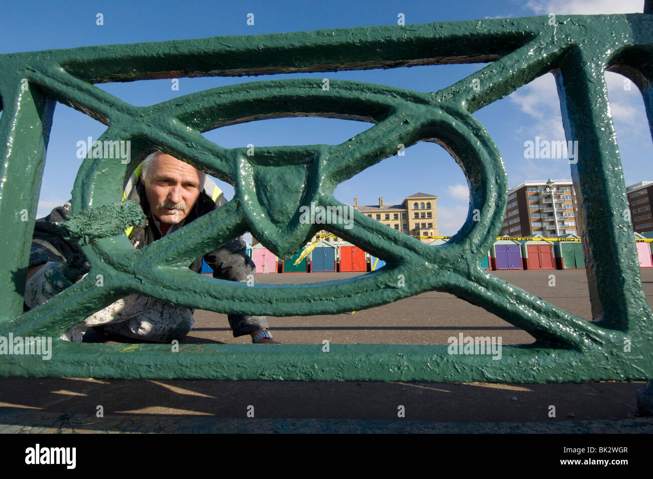 Un dipendente del Consiglio dipinge le ringhiere sul lungomare Hove in primavera, pronto per la stagione estiva. Foto Stock