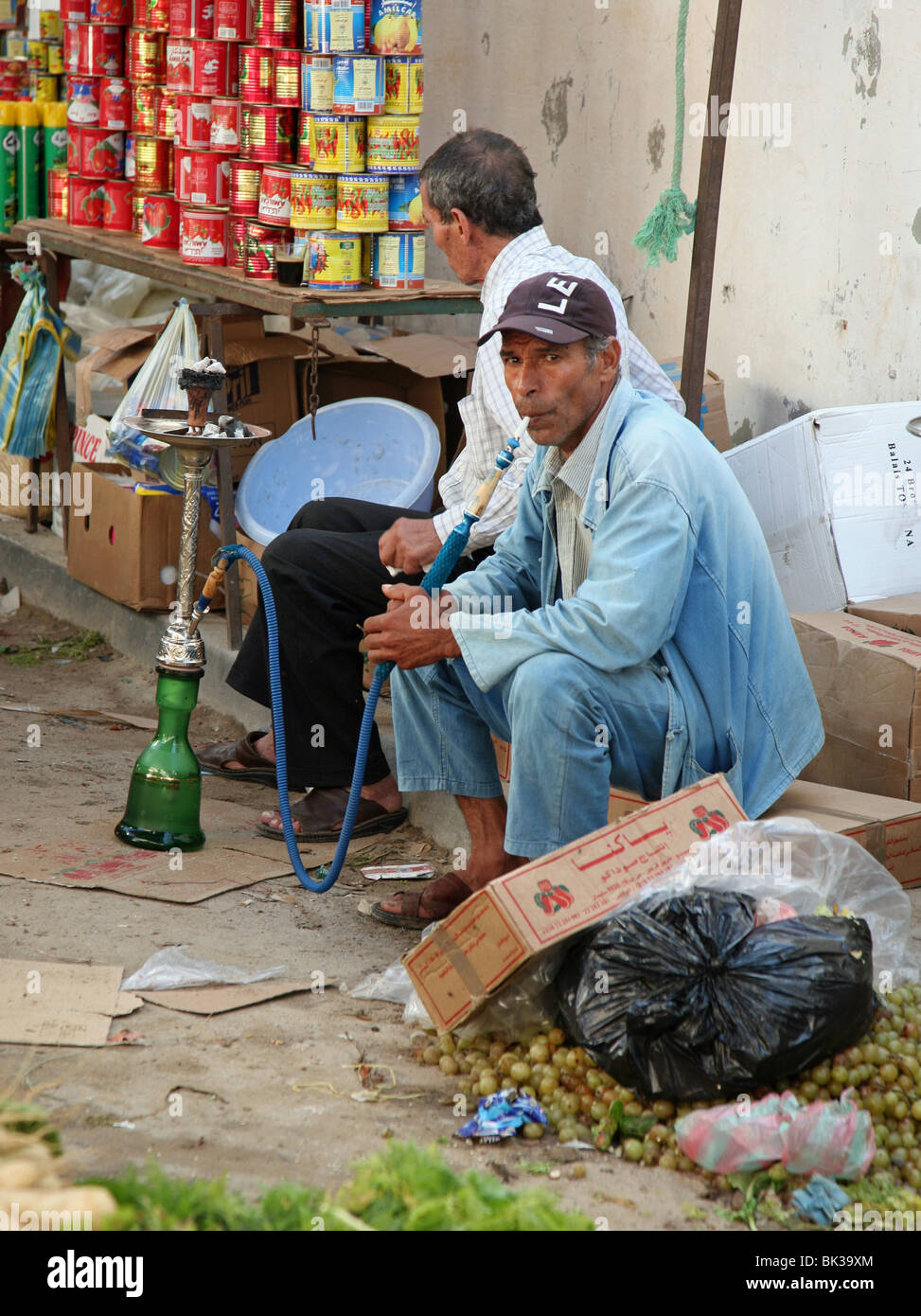 Un locali tunisino uomo fumare una chicha o hookah tubazione in un mercato di frutta e verdura Tunis Tunisia, Nord Africa Foto Stock