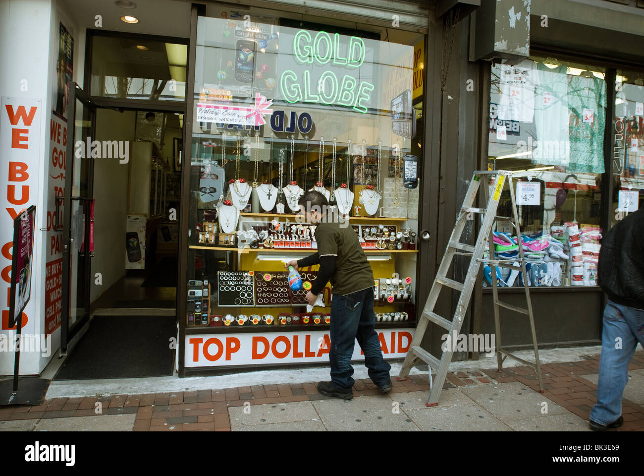 Lavoratore Pulisce vetro anteriore di un negozio gioielli su Market Street nel centro città di Philadelphia, PA Foto Stock