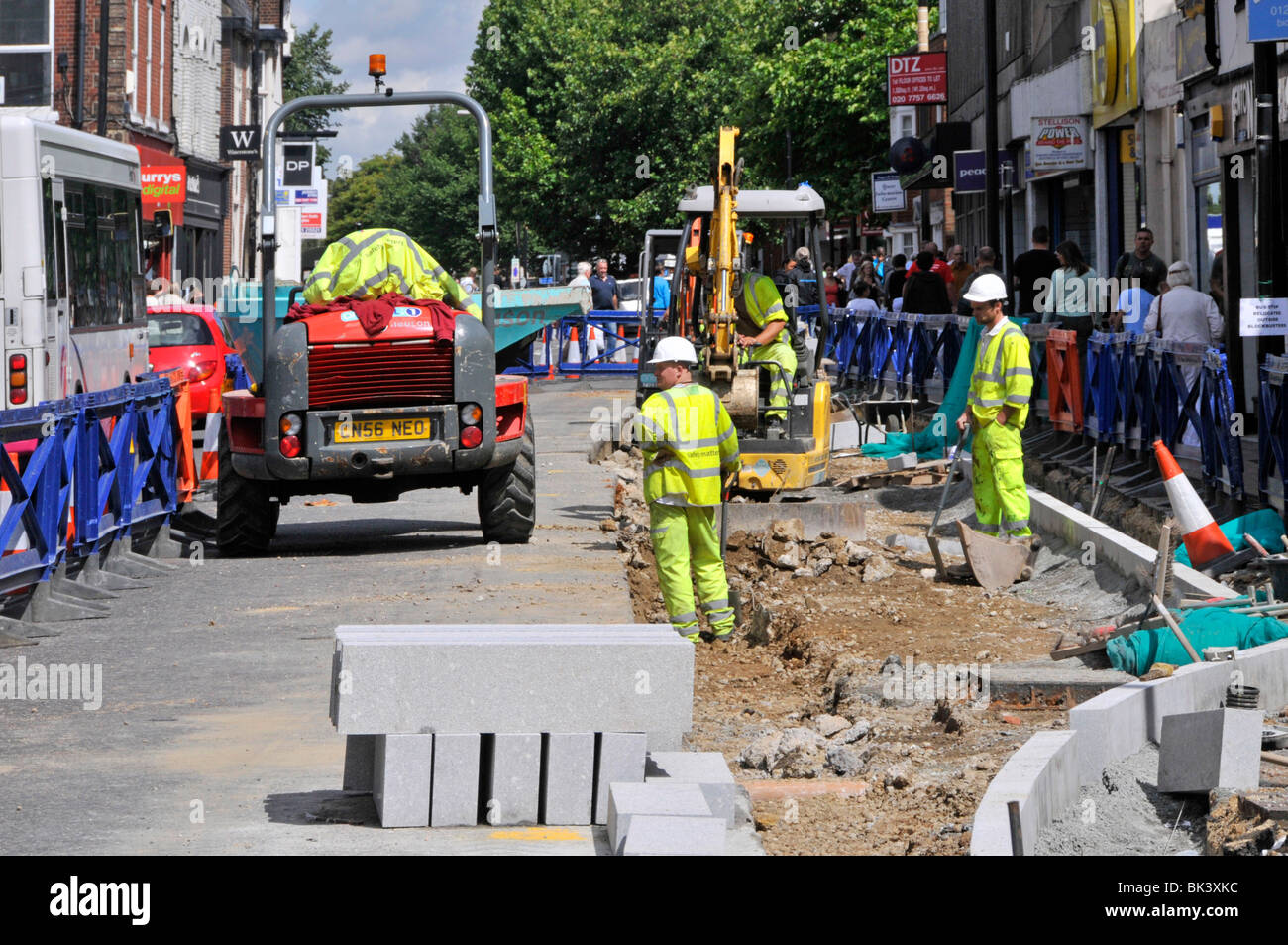 Brentwood Essex shopping High Street Road opere di aggiornamento strade e marciapiedi lavoratori in cappelli duri e giacche ad alta visibilità che lavorano in tutto il Regno Unito acquirenti Foto Stock