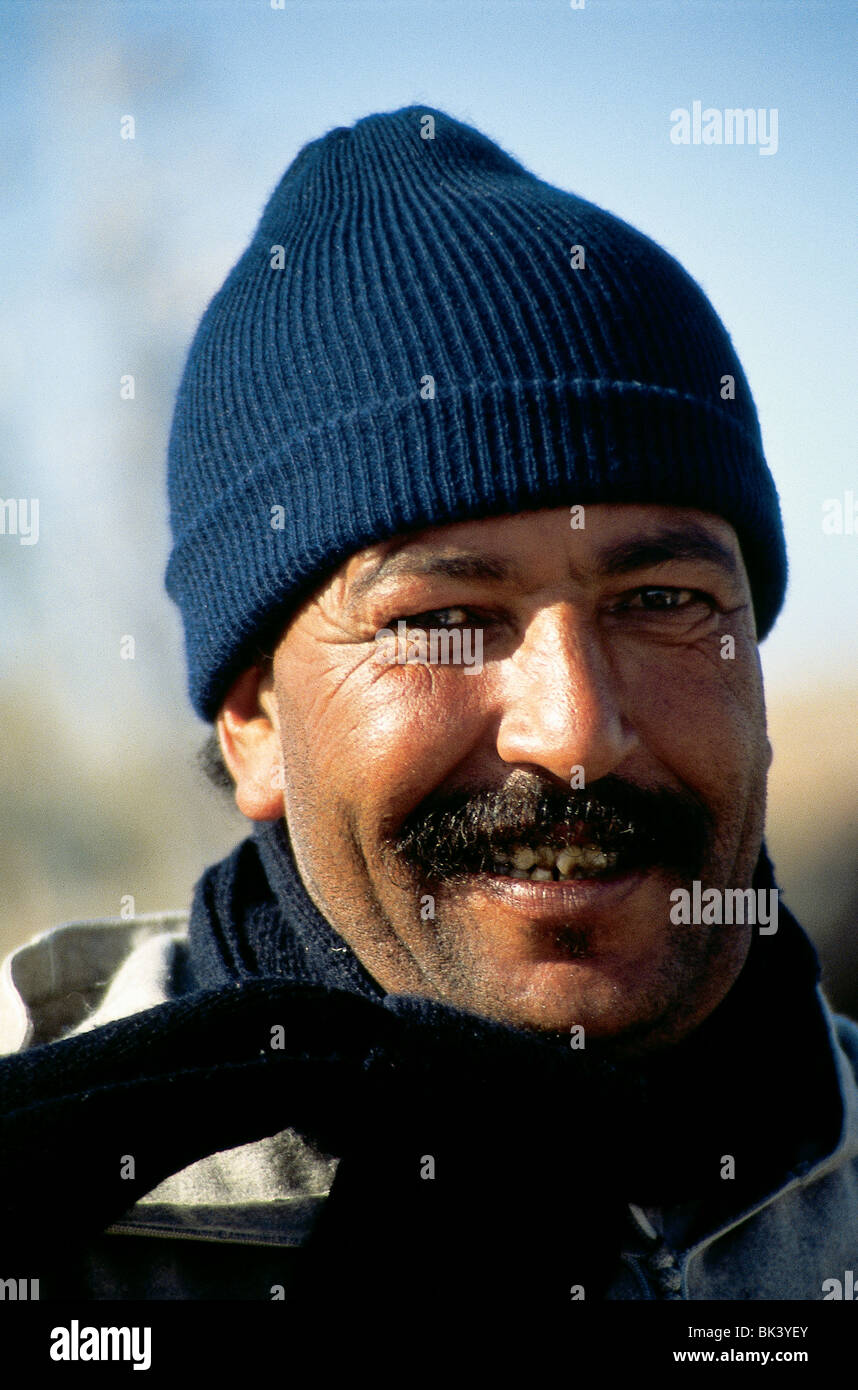 Capo e spalle ritratto di un pescatore che fa contatto con gli occhi mentre indossa una calza a maglia e sciarpa a Safi, Marocco Foto Stock