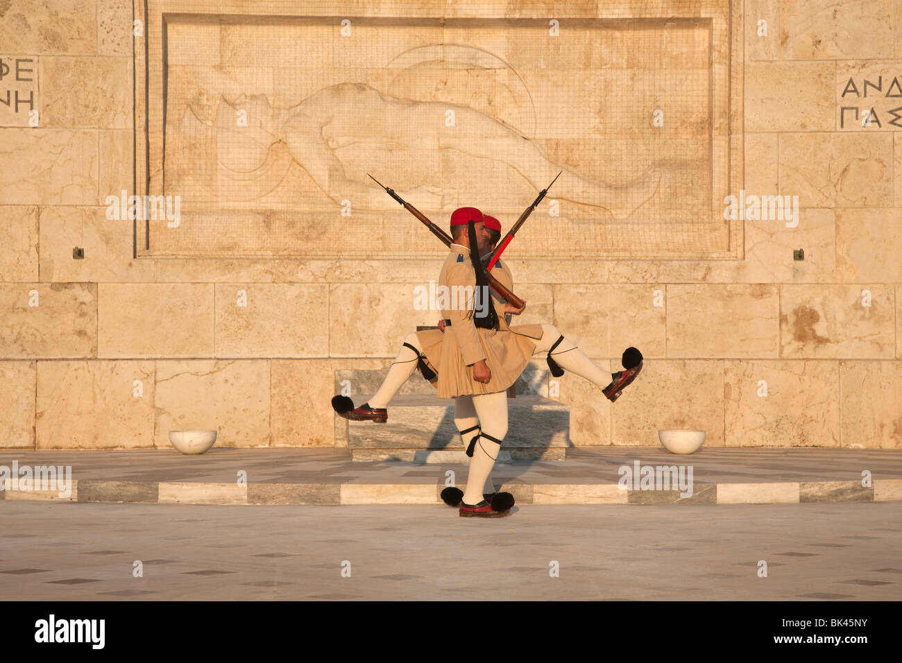Evzones guardia presidenziale marching, alla tomba del Milite Ignoto con la scultura di morire oplita, il parlamento greco ad Atene Foto Stock