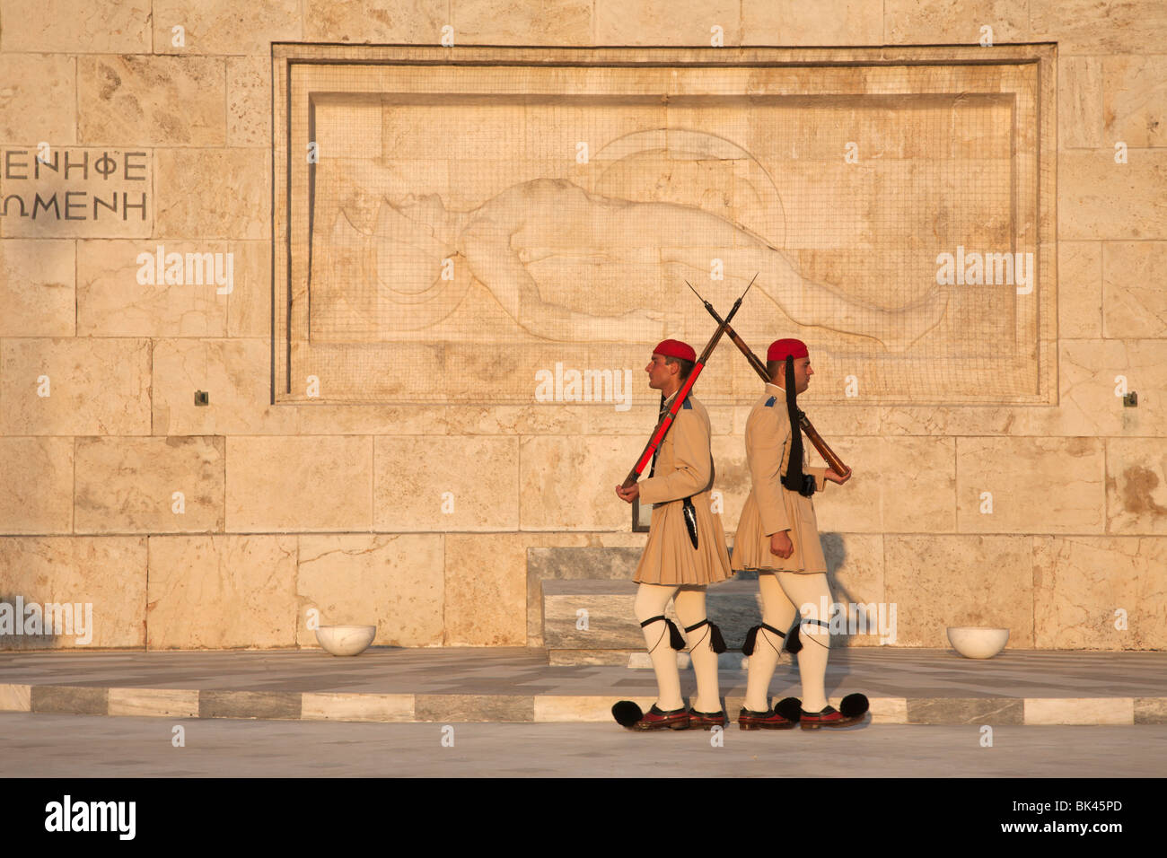 Le guardie presidenziali di Evzones difendono la Tomba del Milite Ignoto con la scultura di un'oplite morente al Parlamento greco di Atene Foto Stock