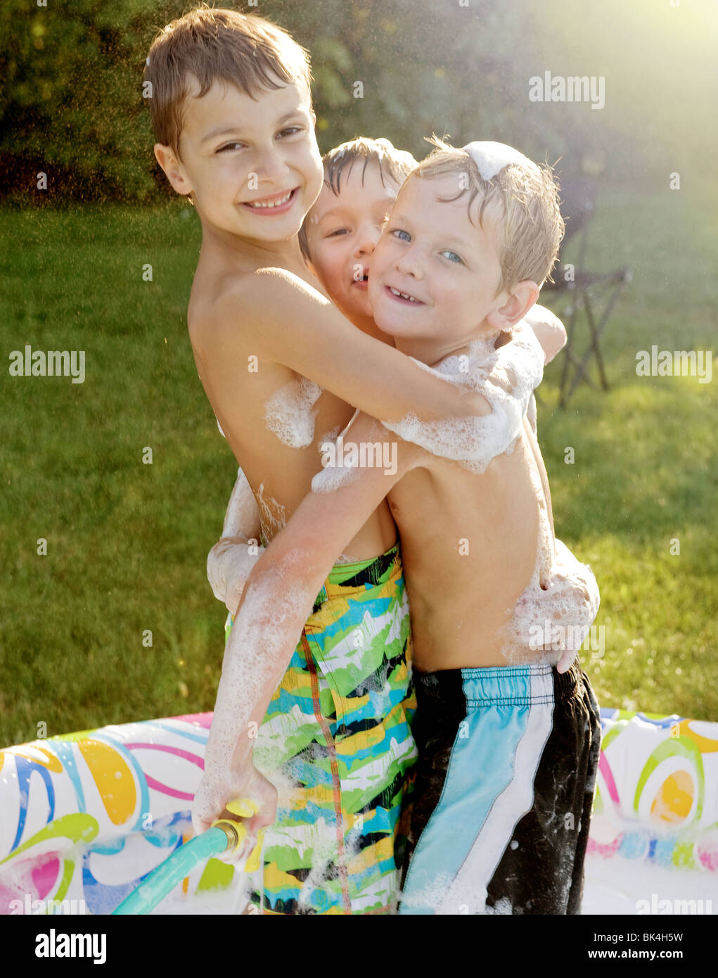 Fratelli abbracciando in piscina per bambini Foto Stock