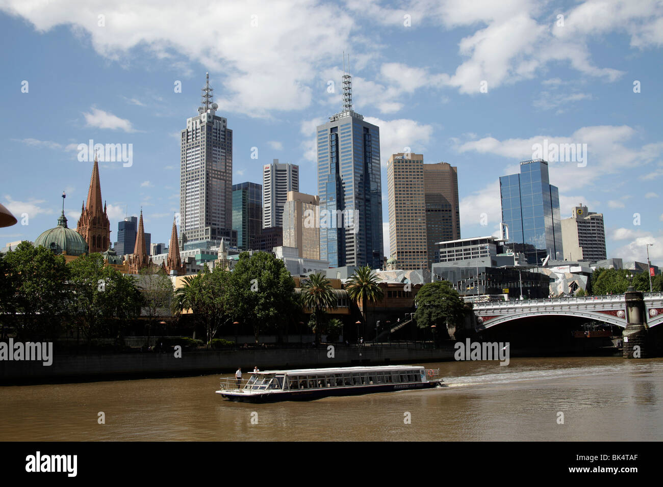 Barca sul Fiume Yarra e la Skyline di Melbourne con la stazione di Flinders Street e le torri della Cattedrale di St Paul, Victoria, Aus Foto Stock