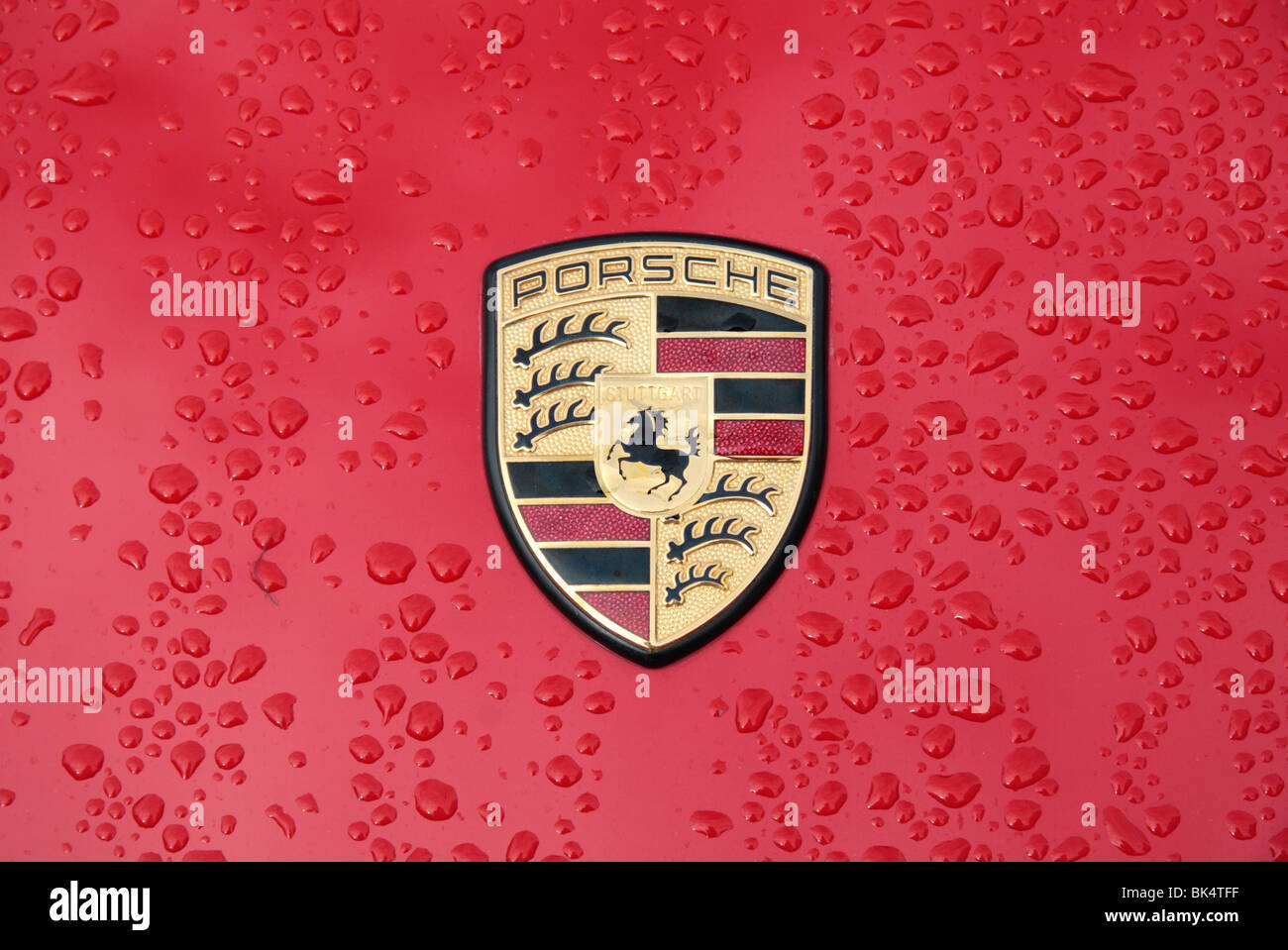 Close up di gocce di pioggia e il badge/logo di un rosso Porsche. Foto Stock