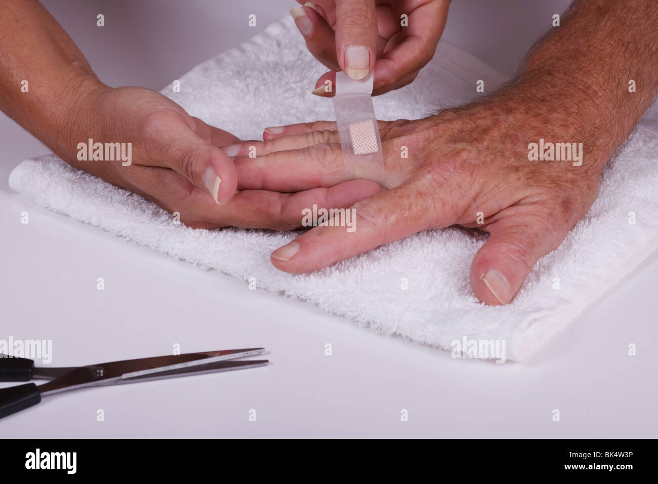 Donna applicando una medicazione ad un uomo del dito. Foto Stock