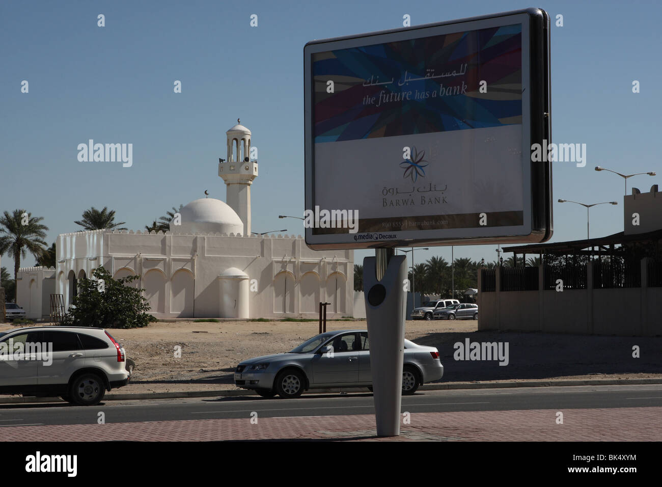 Pubblicità segno di una banca con la moschea in background a Doha, in Qatar Foto Stock