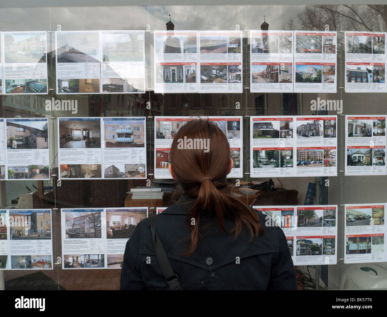 Donna che guarda case in vendita in agenti immobiliari finestra in Utrecht nei Paesi Bassi Foto Stock