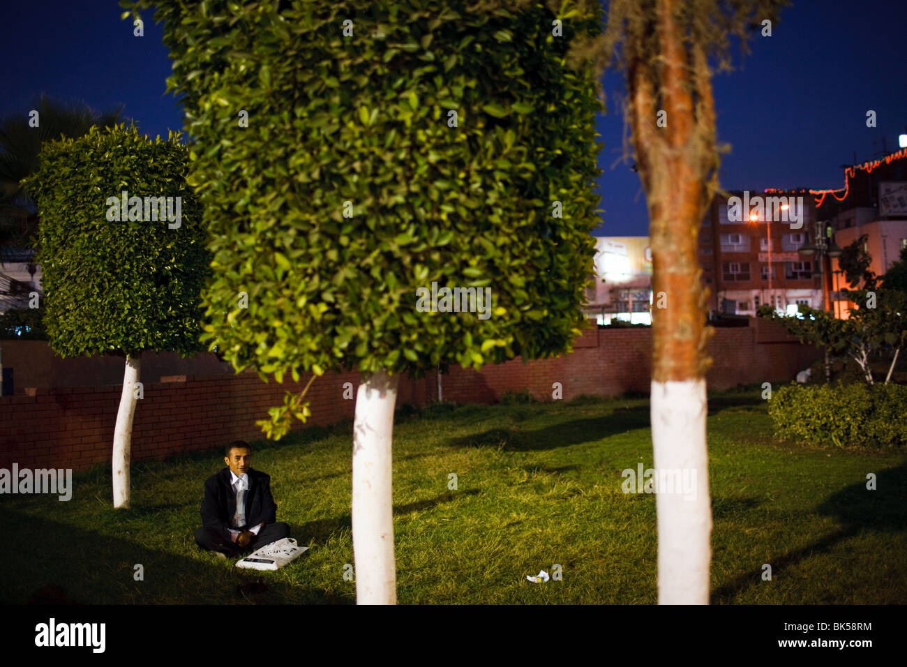 Un uomo si siede sotto un albero a Piazza Tahrir, Sana'a, Yemen Foto Stock