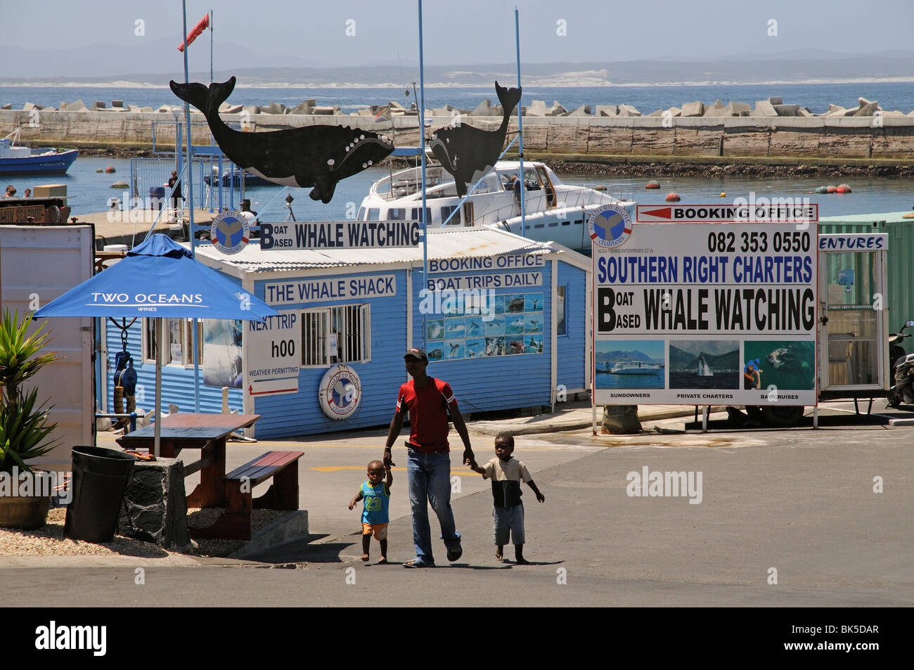 Padre e due figli che camminano sul nuovo porto di Hermanus una località balneare nota per avvistamento di balene Foto Stock