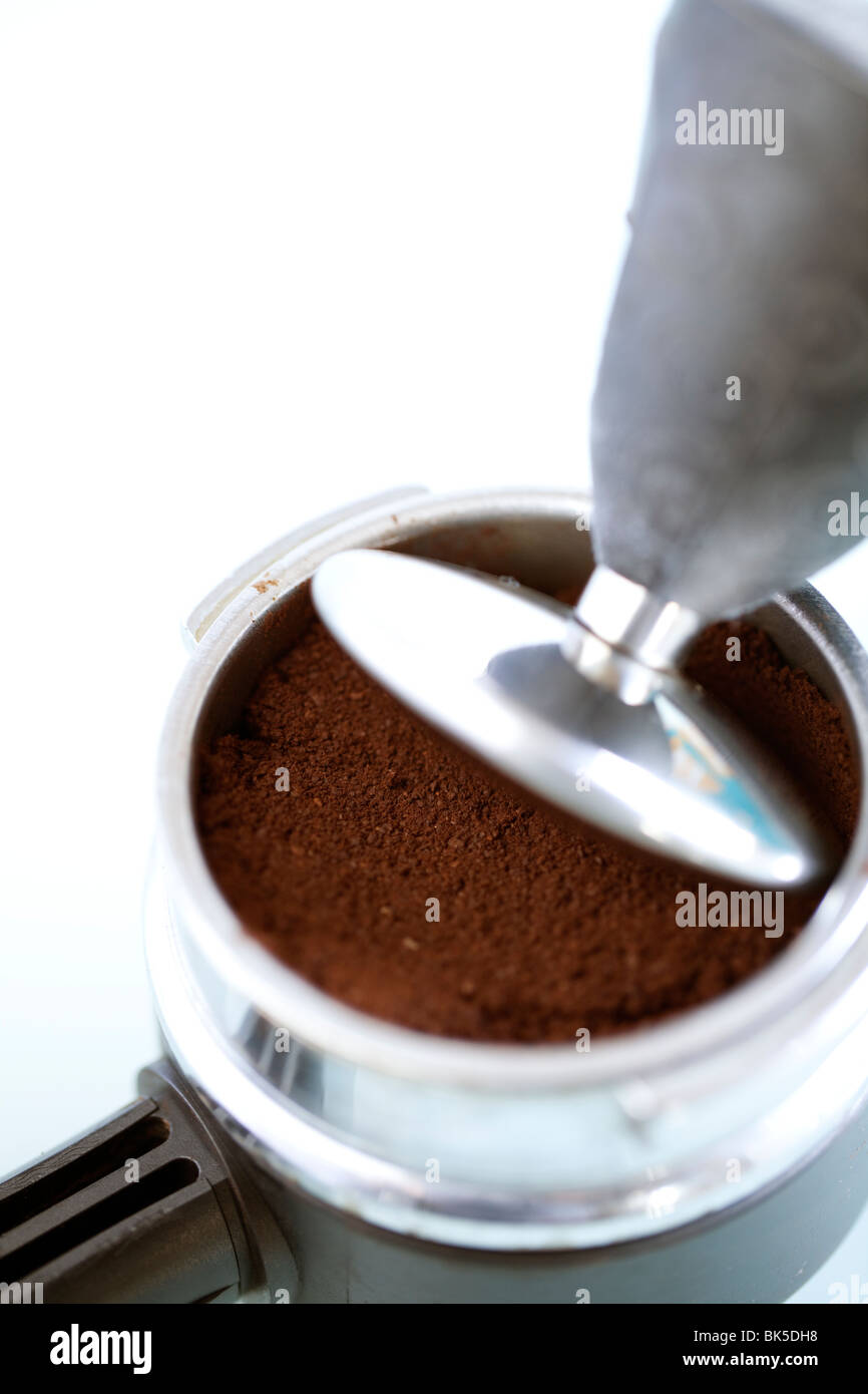Caffè appena macinato in una smerigliatrice titolare viene premuto verso il basso pronto a fare il caffè fresco o espress Foto Stock