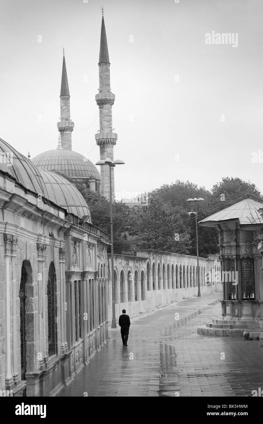 Uomo che cammina sulla pioggia-imbevuta street, Istanbul, Turchia Foto Stock