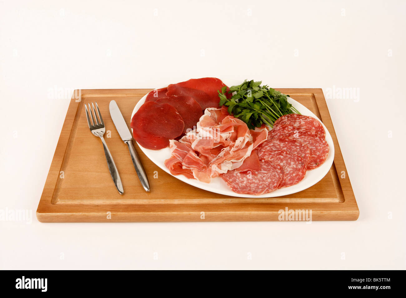 Un piatto di salumi italiani con salame e bresaola su un tagliere di legno Foto Stock