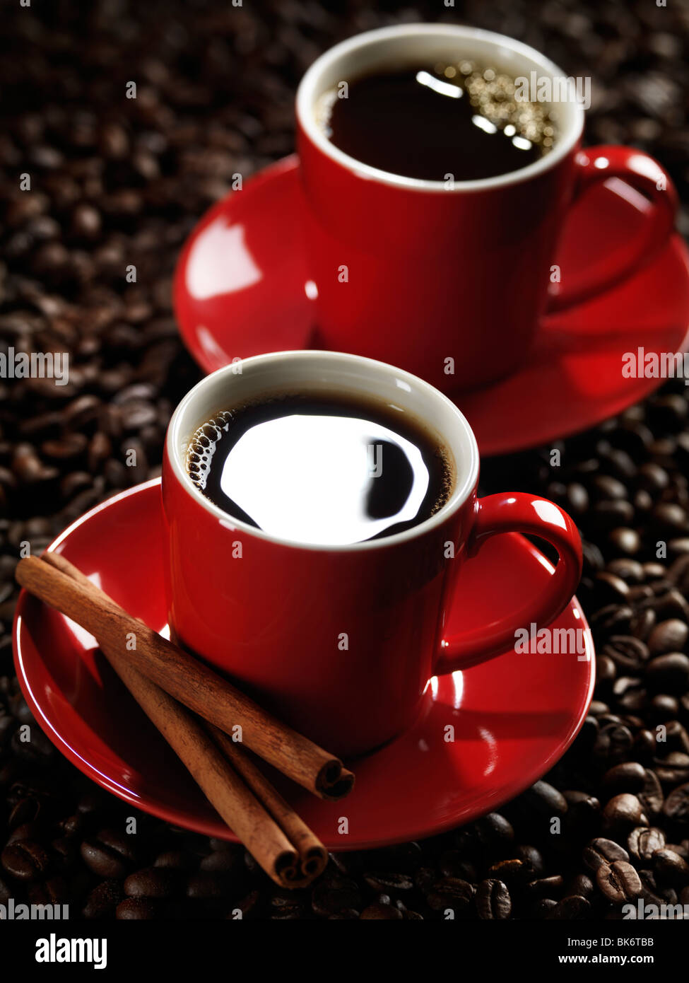 Rosso di due tazze di caffè in chicchi di caffè sfondo Foto Stock