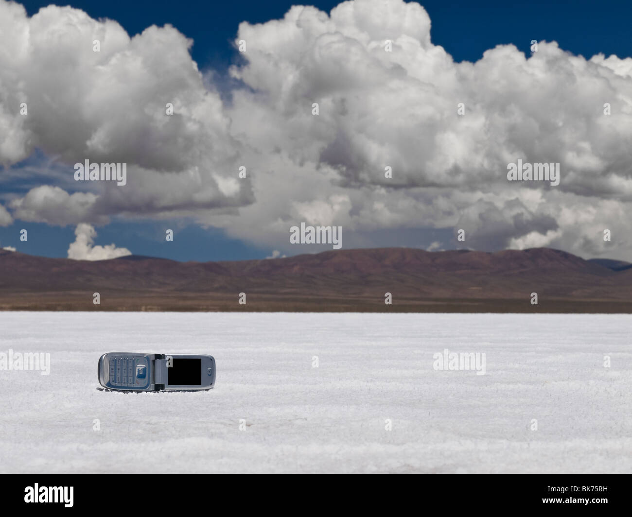Un telefono cellulare abbandonato su un campo di sale. Le montagne sullo sfondo. Foto Stock
