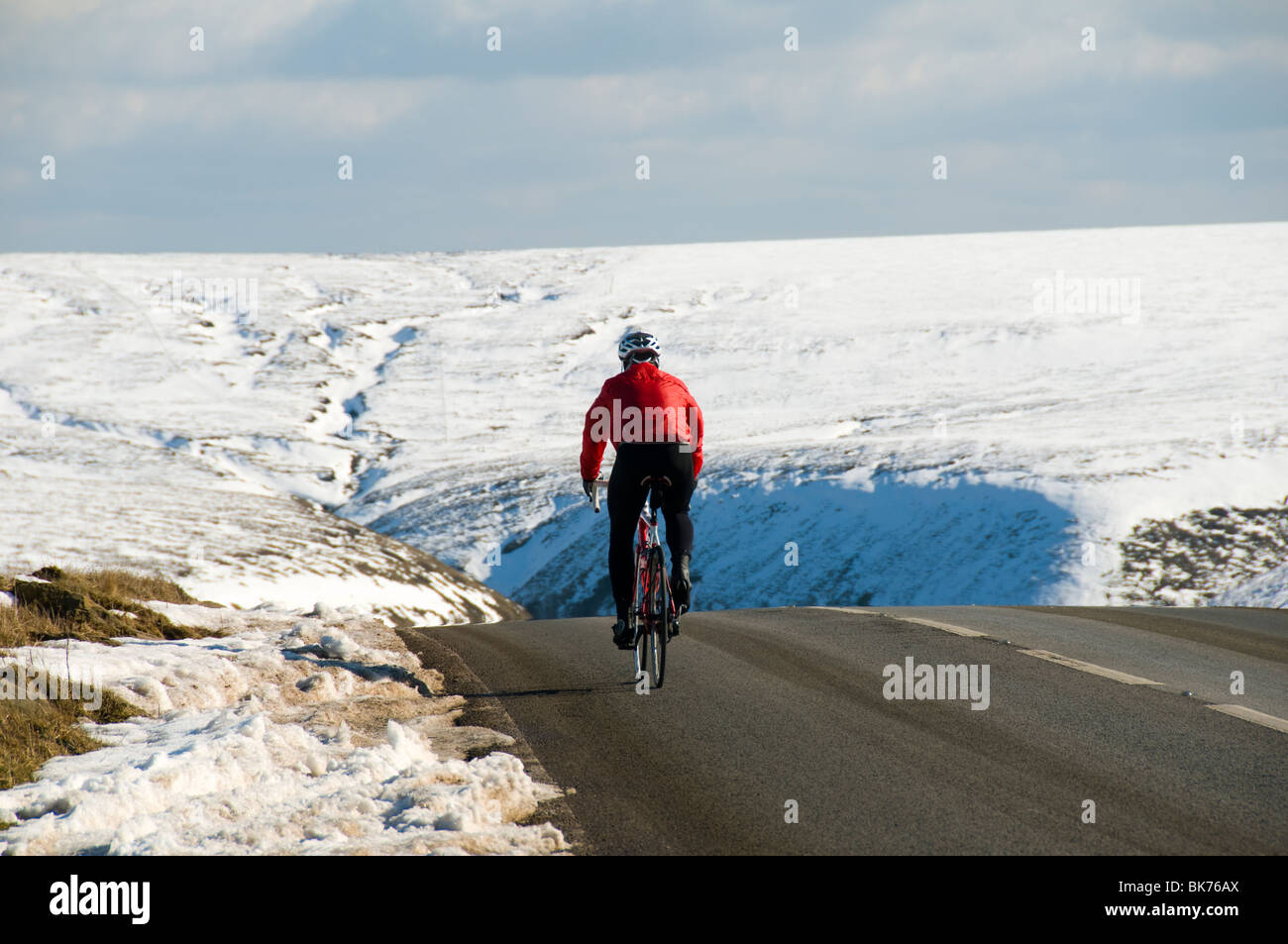 Ciclista sulla A57 Snake pass road in inverno, vicino a Glossop, Peak District, Derbyshire, England, Regno Unito Foto Stock