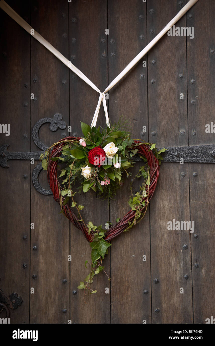 A forma di cuore ghirlanda di vimini con fiori e nastro Foto stock - Alamy