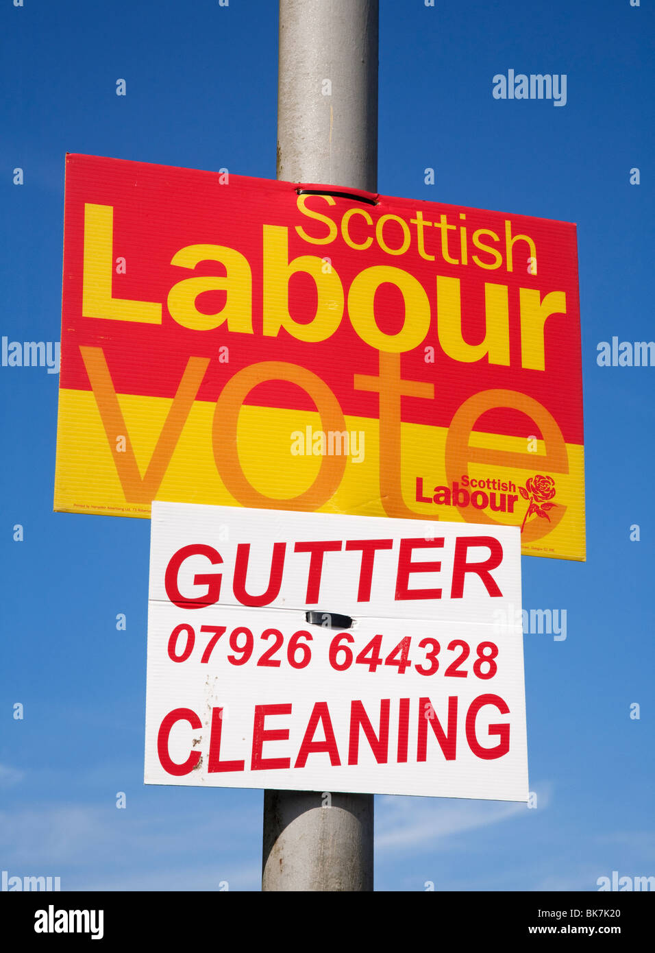 Un divertente lavoro 2010 cartellone elettorale su un lampione sopra un altro segno per la pulizia di gronda. Foto Stock