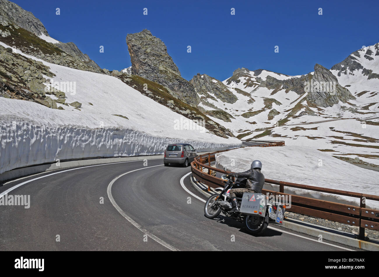 Monovolume auto e moto pass snow drift argini sulla salita di SS27 strada di montagna che conduce al Colle del Gran San Bernardo Italia Foto Stock