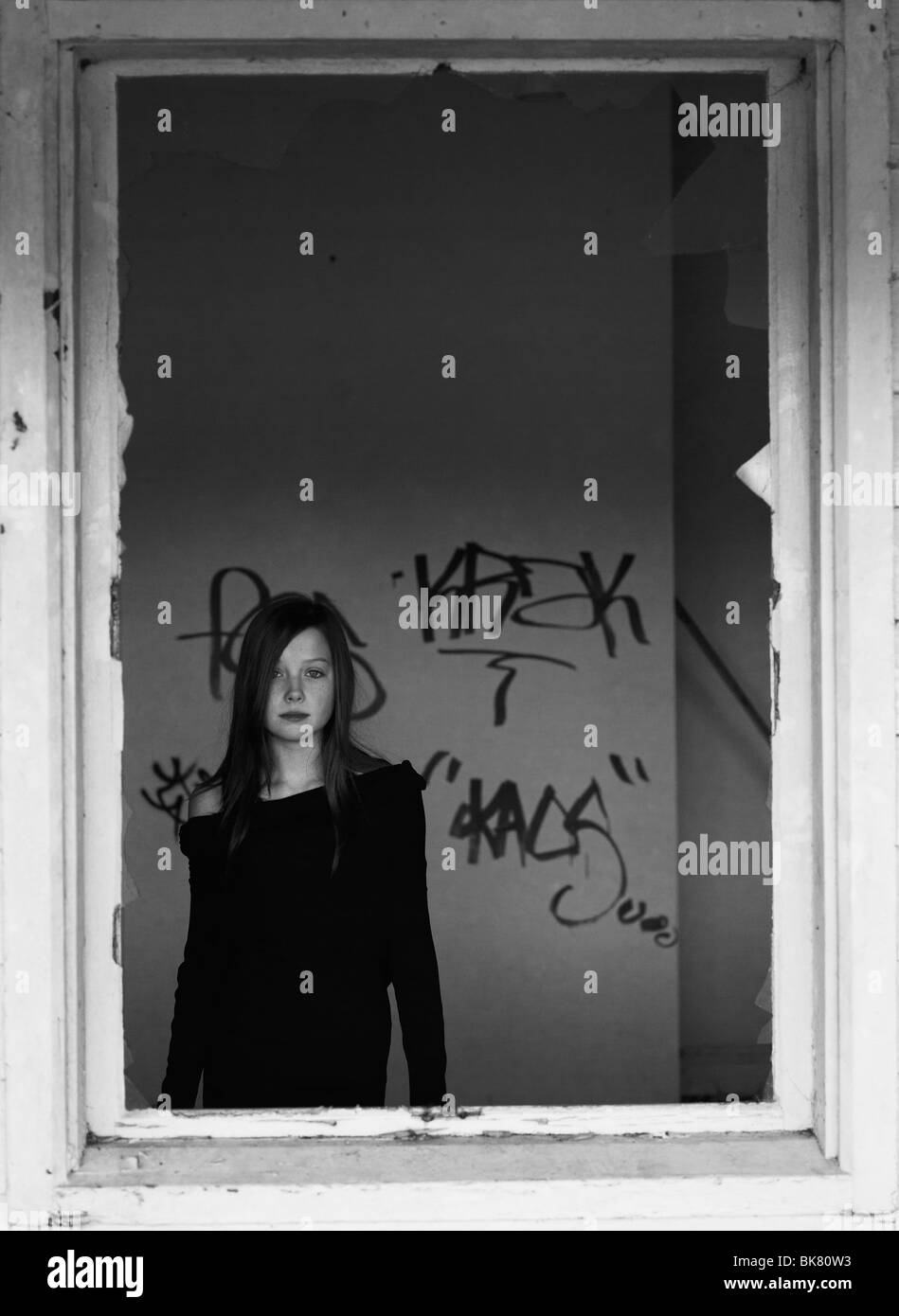 Bianco e nero ritratto di una ragazza che guarda fuori di un telaio di una finestra Foto Stock