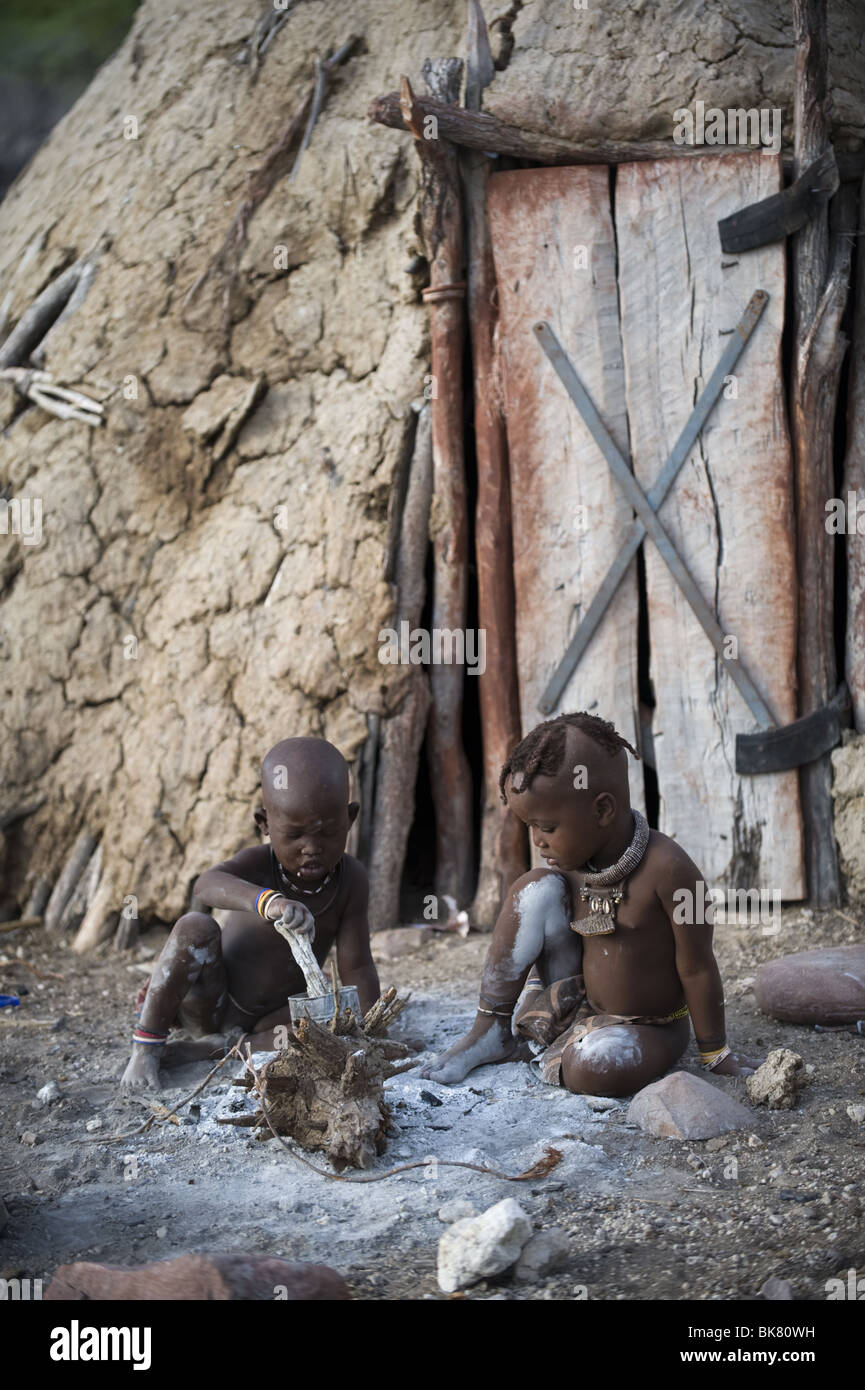 Himba bambini che giocano al di fuori della loro capanna, Kaokoland, regione di Kunene, Namibia. Foto Stock