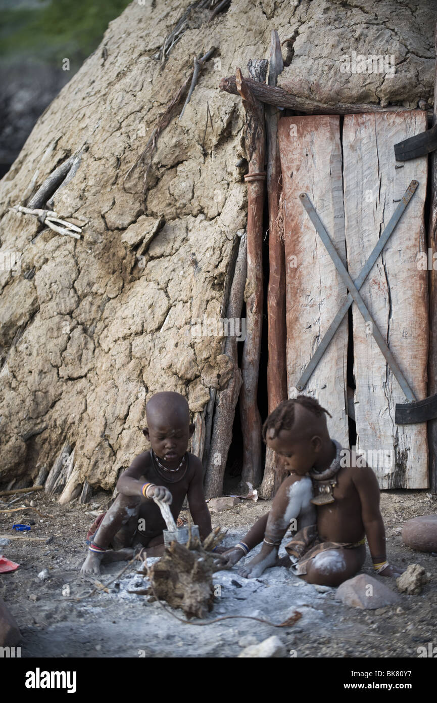 Himba bambini che giocano al di fuori della loro capanna, Kaokoland, regione di Kunene, Namibia. Foto Stock