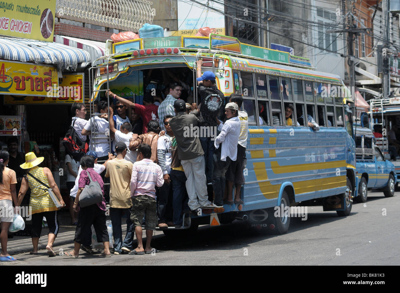 Persone che cercavano di salire a bordo di un autobus affollato in Thailandia Foto Stock