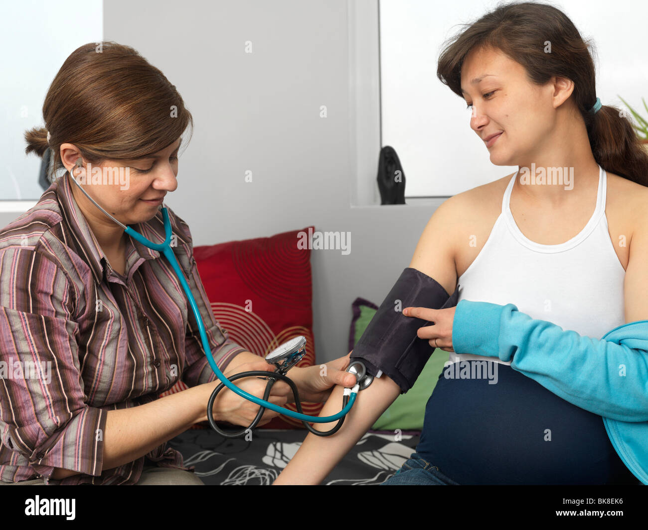 La levatrice la misura della pressione del sangue di una donna in stato di gravidanza Foto Stock