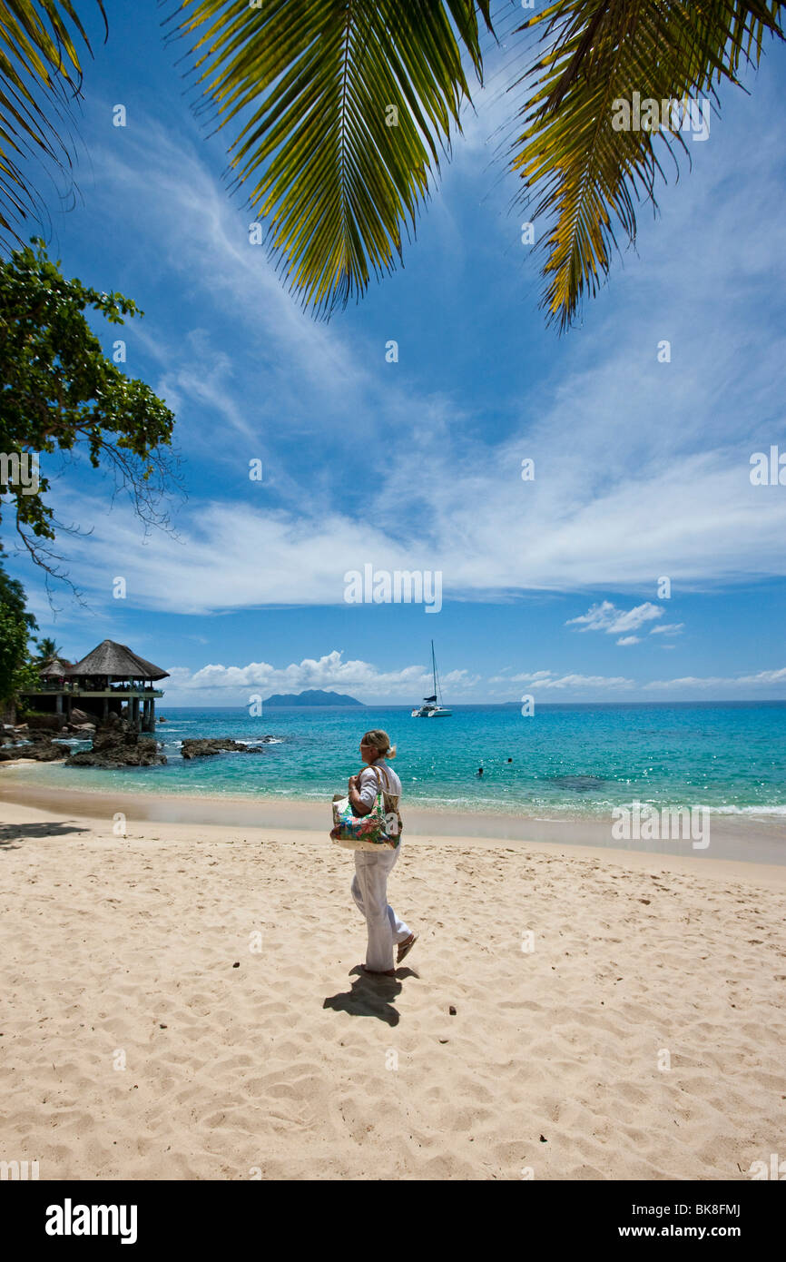 Donna che cammina su una spiaggia vicino Glacis, Isola di Mahe, Seychelles, Oceano indiano, Africa Foto Stock
