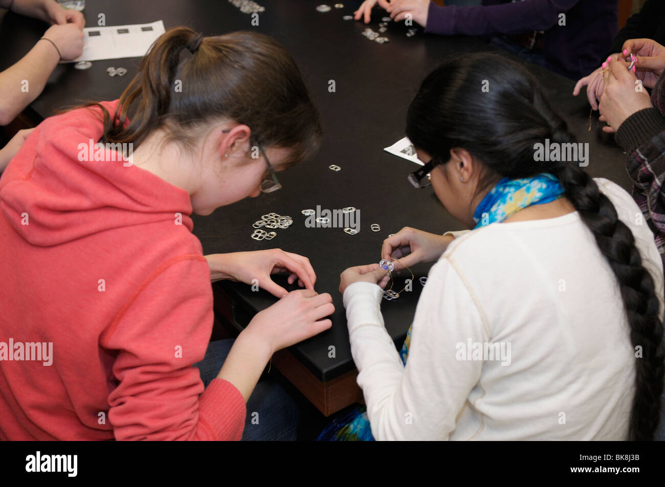 Alta scuola ambientale riunione del club. Gli studenti utilizzano il carbonato di sodio può flip top per la realizzazione di bracciali di vendere come una raccolta di fondi Foto Stock
