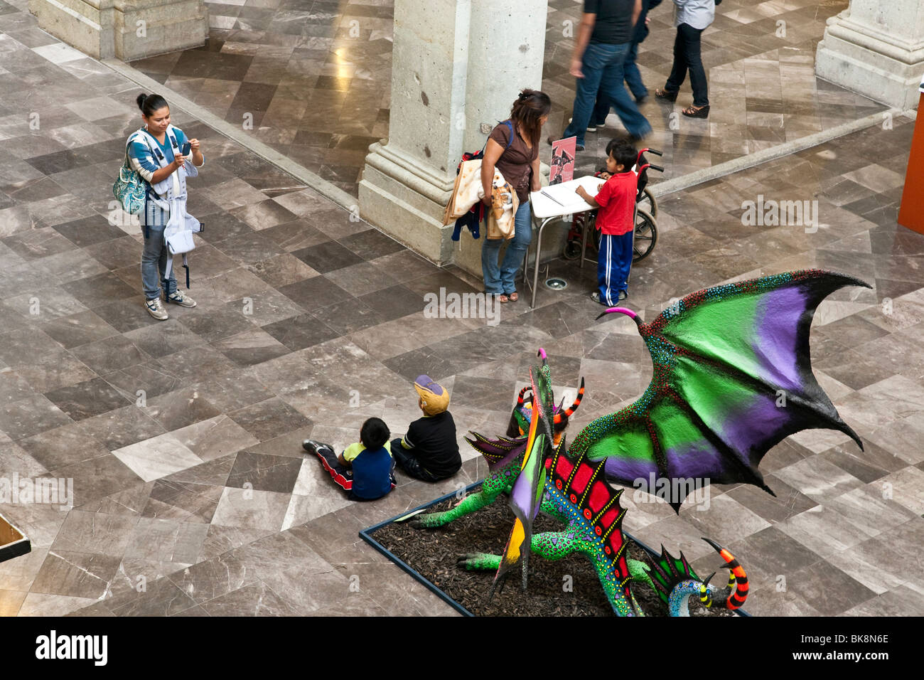 Due piccolo messicano ragazzi costituiscono per la loro mamma orgogliosa di fronte fantastica dragon scultura in mostra al Palazzo dei Governatori Oaxaca Foto Stock