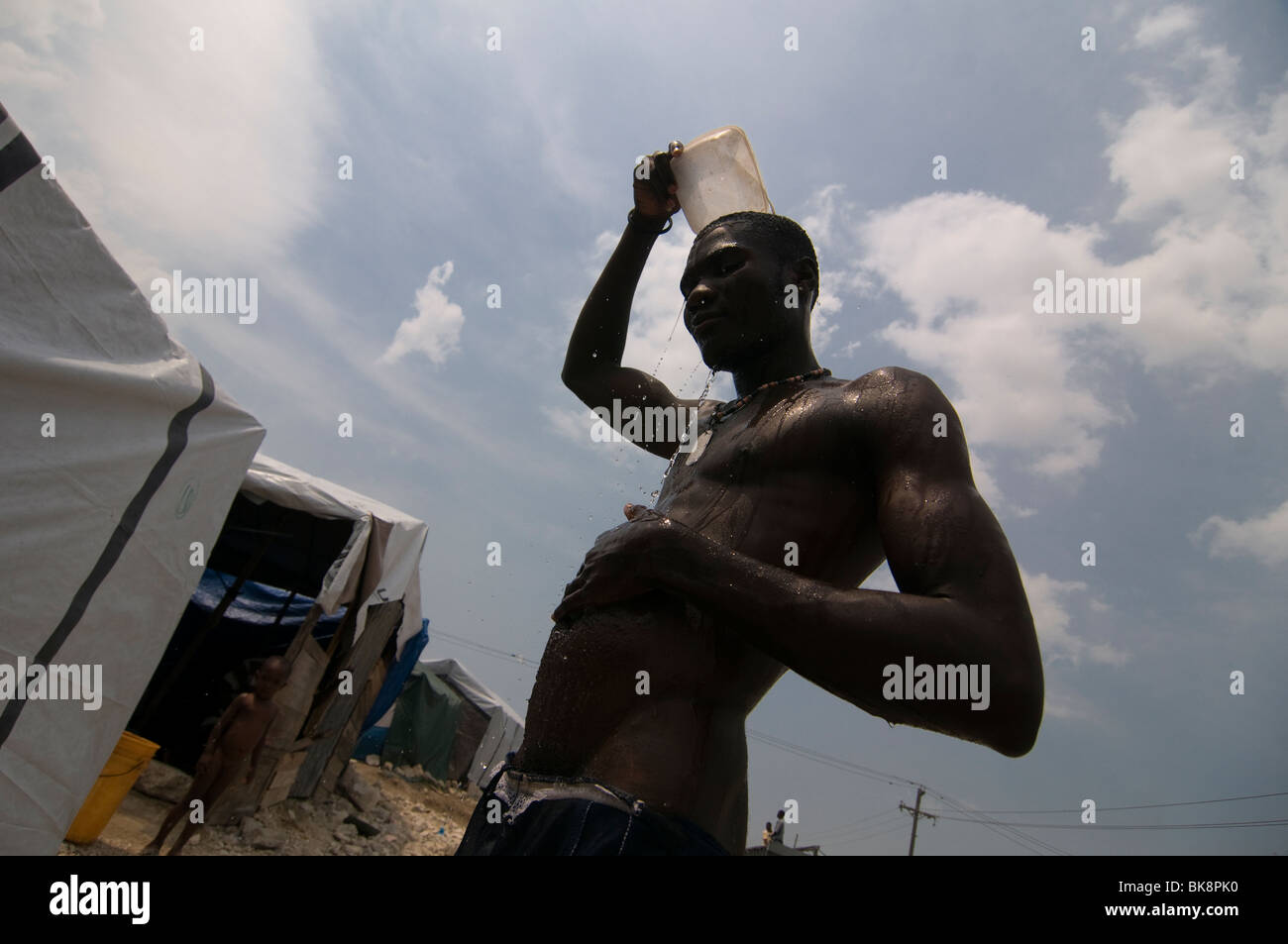 Un uomo lava fino in un campo di fortuna per i superstiti di un terremoto di magnitudine 7.0 che ha colpito Haiti il 12 gennaio 2010 a Port-au-Prince Foto Stock