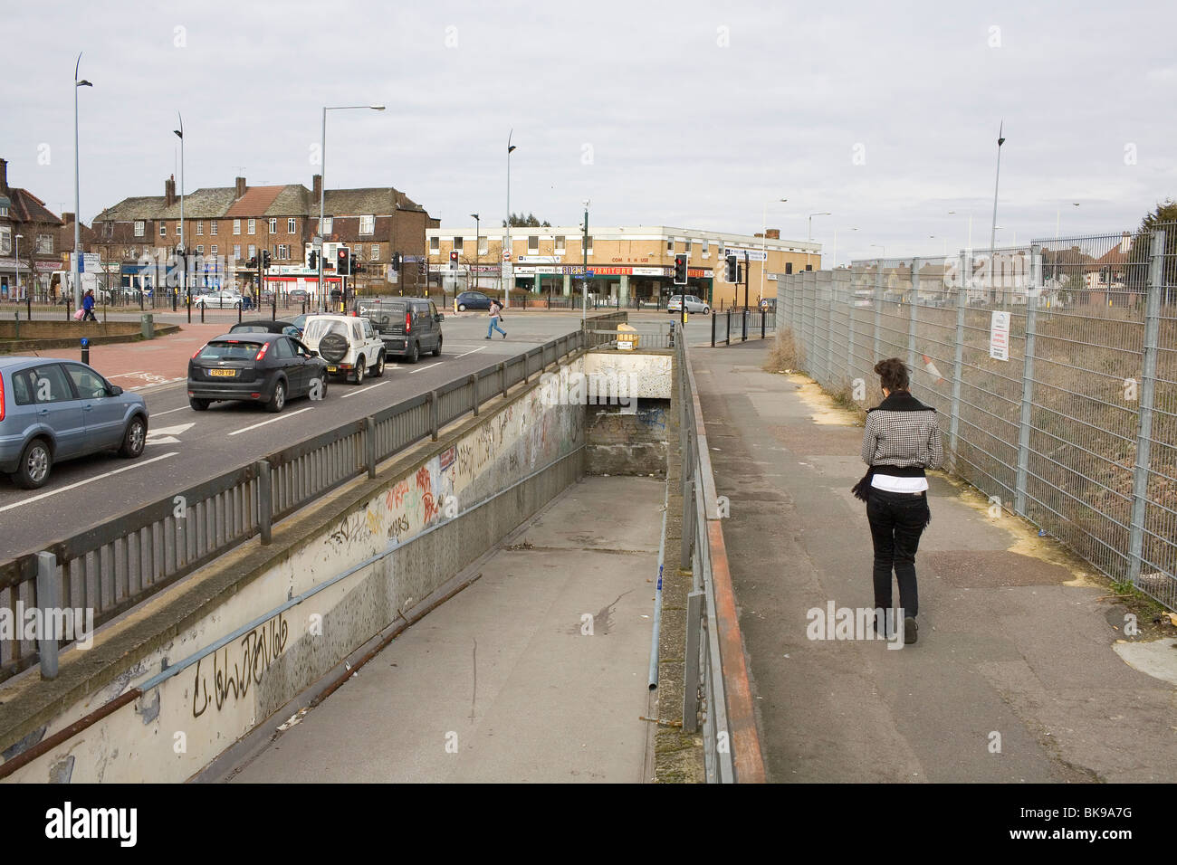 Una giovane donna cammina passato una murata alla metropolitana nella zona est di Londra sobborgo di Dagenham. Foto Stock